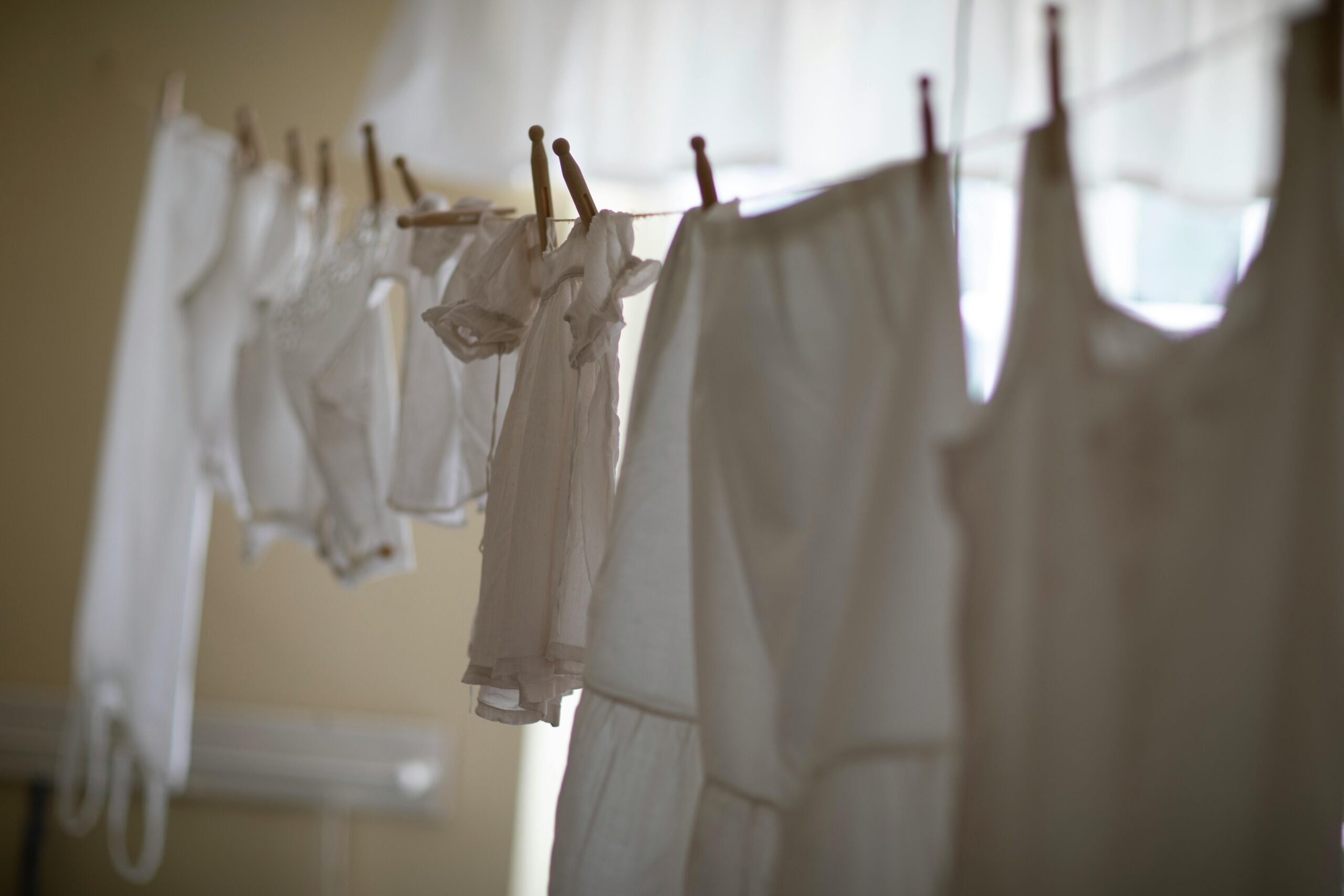 Services A row of white clothing hangs on a clothesline indoors, softly lit.
