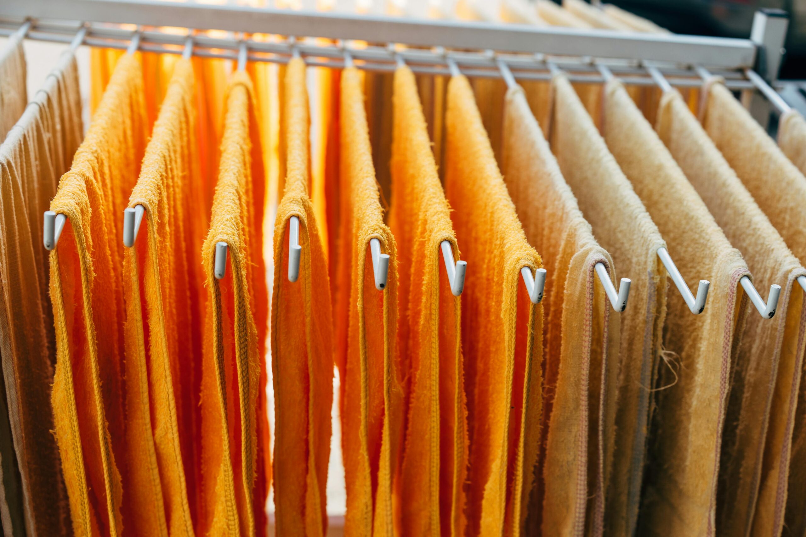 Services Vibrant orange and beige towels neatly hang on a drying rack indoors.