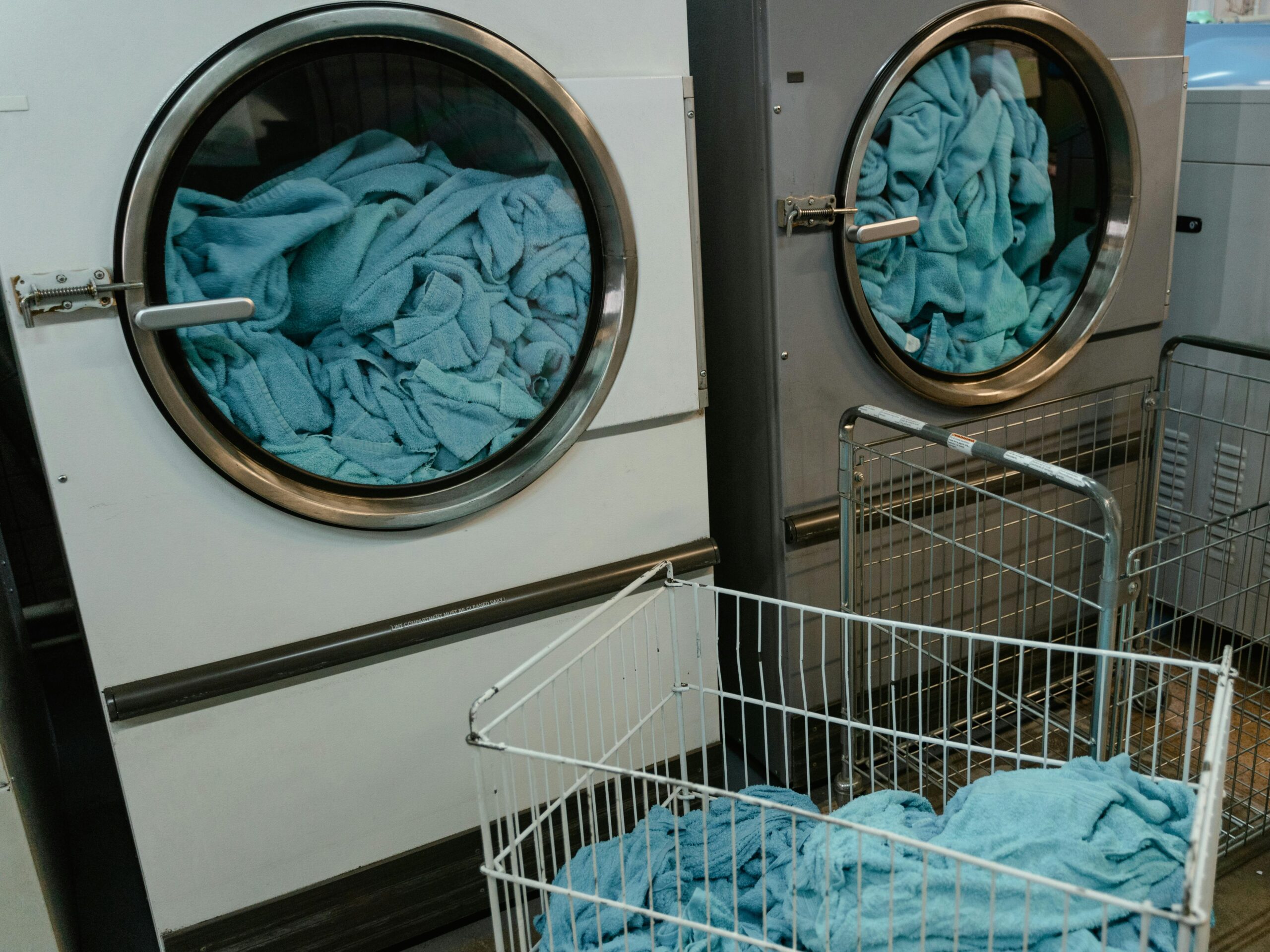 Services Industrial washing machines with blue towels in a laundry facility.